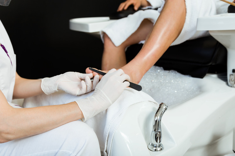 Portrait of young man doing pedicure in salon. Beauty concept.